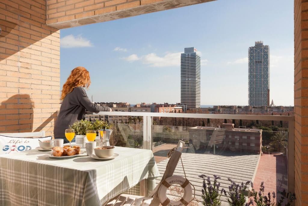 A balcony with a table set for breakfast, a view of the cityscape, and a life preserver hanging on the railing.