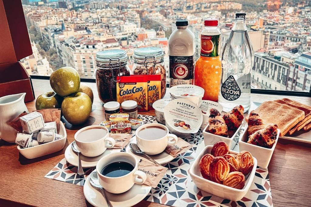 Ein reichhaltiges Frühstück mit verschiedenen Speisen und Getränken auf einem Tisch mit Blick auf die Stadt.