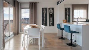 A modern kitchen with a dining area, large windows, and a view of the city. - ENJOYBCN MARINA APARTMENT (Barcelona)