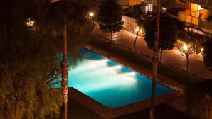 A rectangular swimming pool with a water fountain, surrounded by trees and a paved walkway. - ENJOYBCN MARINA APARTMENT (Barcelona)