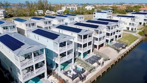 A coastal residential area with multiple two-story houses featuring balconies and solar panels. - Canalfront! Pool, Dock, Near Anna Maria Island (Cortez)
