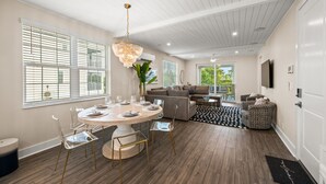 A modern living room with a dining area, featuring a round table, chairs, a sofa, and a television. - Canalfront! Pool, Dock, Near Anna Maria Island (Cortez)