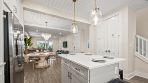 A modern kitchen with a central island, white cabinetry, and a dining area with a round table and chairs. - Canalfront! Pool, Dock, Near Anna Maria Island (Cortez)