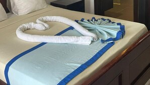 Una habitación de hotel con cama, mesita de noche, un cuadro en la pared y una puerta abierta que da a un baño.