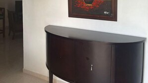 Una consola de madera oscura con un jarrón y flores en la pared de encima.