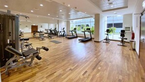 A spacious gym with various exercise equipment, large windows, and a wooden floor. - Premium 1 Bed | Walk to Dubai Mall, Burj Khalifa (Downtown Dubai)