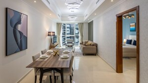 A modern hotel room with a dining area, a sofa, and a large window with a city view. - Premium 1 Bed | Walk to Dubai Mall, Burj Khalifa (Downtown Dubai)