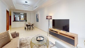 A modern living room with a sofa, TV stand, and dining area. - Premium 1 Bed | Walk to Dubai Mall, Burj Khalifa (Downtown Dubai)