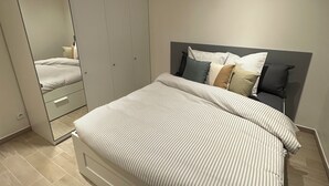Et moderne soveværelse med en stor seng, et garderobeskab og et spejl.