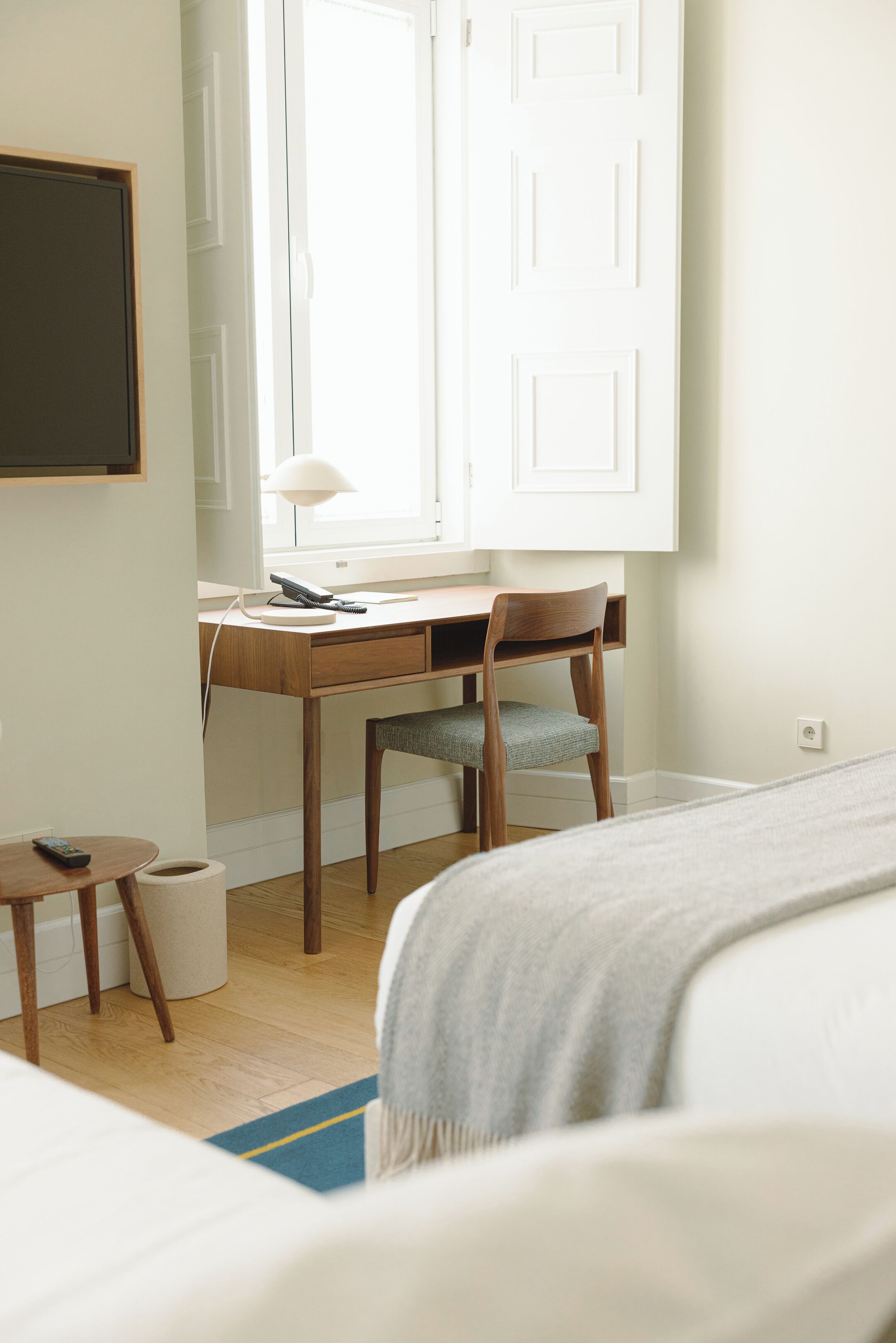 Une chambre d’hôtel avec un bureau en bois, une chaise, un lit et une fenêtre donnant sur un paysage agréable.