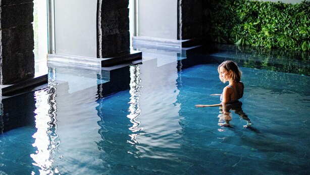 An indoor swimming pool with arched ceilings and a clear view of the pool's edge.