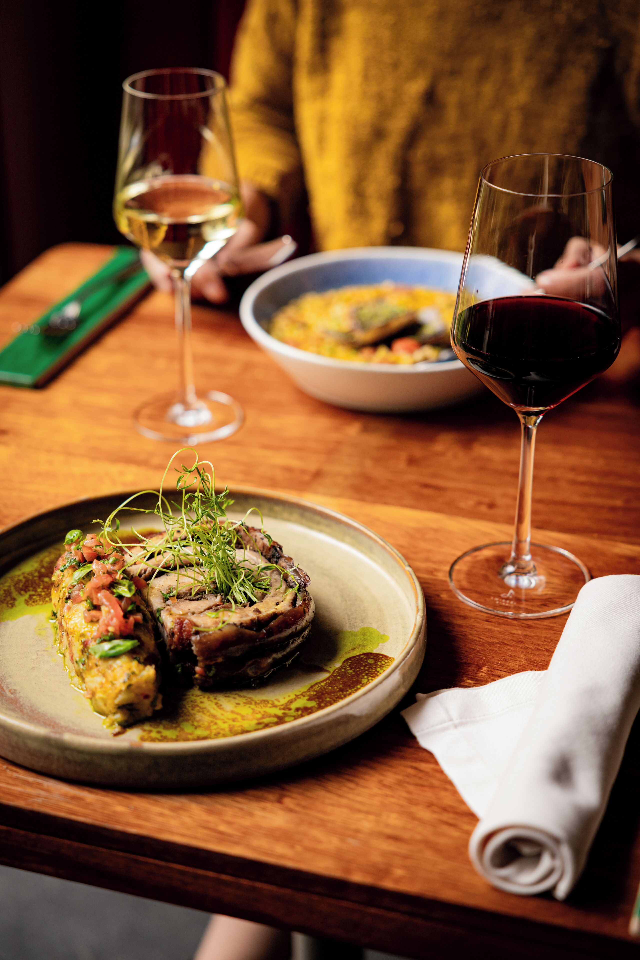 A wooden table with a plate of food and two wine glasses.