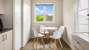 Una cucina compatta con angolo pranzo, un'ampia finestra vista su spazi verdi e un lampadario moderno.