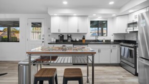 A modern kitchen with white cabinets, stainless steel appliances, a tiled backsplash, and a skylight. - Spacious Tucson OASIS 4BD/2.5BA, Sparkling Pool, Billiards, Pingpong, Family-Fun (Tucson)