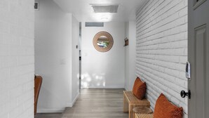 A hallway with white brick walls, wooden benches, and a ceiling light. - Spacious Tucson OASIS 4BD/2.5BA, Sparkling Pool, Billiards, Pingpong, Family-Fun (Tucson)