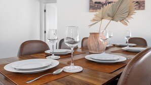 A dining table set with plates, glasses, and cutlery, with a vase of dried leaves and a painting on the wall. - Spacious Tucson OASIS 4BD/2.5BA, Sparkling Pool, Billiards, Pingpong, Family-Fun (Tucson)