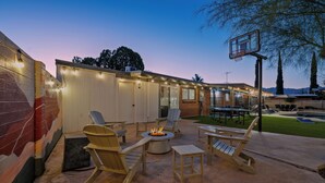 An outdoor patio with wooden furniture, a fire pit, and a basketball hoop. - Spacious Tucson OASIS 4BD/2.5BA, Sparkling Pool, Billiards, Pingpong, Family-Fun (Tucson)