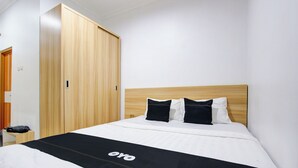 Una habitación de hotel con cabecera de madera, cama con ropa de cama blanca y negra, y una colcha negra con la palabra 'oyo'.