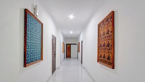 Un pasillo con paredes blancas, piso de mármol y grandes obras de arte decorando ambos lados.