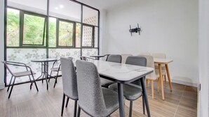 Un comedor con un ventanal grande, un televisor montado en la pared y una mesa con sillas.