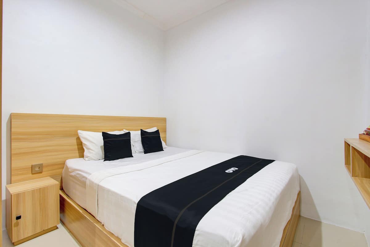 A neatly made bed with a wooden headboard, a bedside table, and a small wooden cabinet.