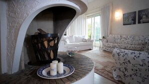 A cozy living room with a fireplace, a white sofa, and floral-patterned cushions. - Regarda - "Villa Infinity" with private pool and lake view (Bardolino)