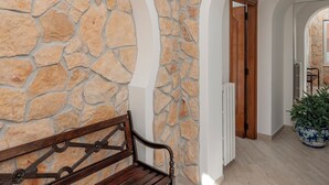 A hallway with stone walls, wooden door, and a bench. - alle Stelle b&b (Anacapri)