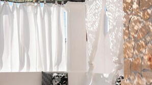 A room with a white sofa, a wooden table with a plant, and a patterned pillow. - alle Stelle b&b (Anacapri)