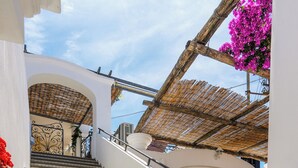A staircase with patterned tiles leading to an upper level, a wooden chair, and a thatched roof structure. - alle Stelle b&b (Anacapri)