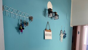 A room with a teal wall, a wooden bench with a 'HOME' sign, a calendar, a small plant, and a book. - Appartement en Sicile Près de la mer Pour 1-6 Personnes Avec Terrasse et Wifi (Balestrate)