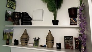 En hylde med dekorative genstande, herunder en potteplante, vaser og bøger.