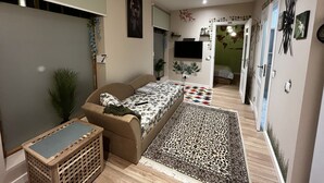 Et soveværelse med en seng, en lille sofa, et fjernsyn og et verdenskort på væggen.