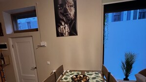 En spiseplads med et bord, stole, en lysekrone, et billede på væggen og et vindue med udsigt.