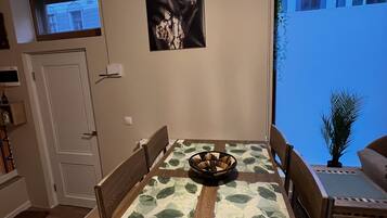 Un espace repas comprenant une table, des chaises, un lustre, une œuvre d’art accrochée au mur et une fenêtre donnant sur un paysage.