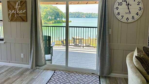 A room with a large window overlooking a lake, a clock on the wall, and a 'gather together' sign. - STAY HERE! 2 Homes sleep up to 28! Private cove 2 docks and personal boat launch (Sevierville)