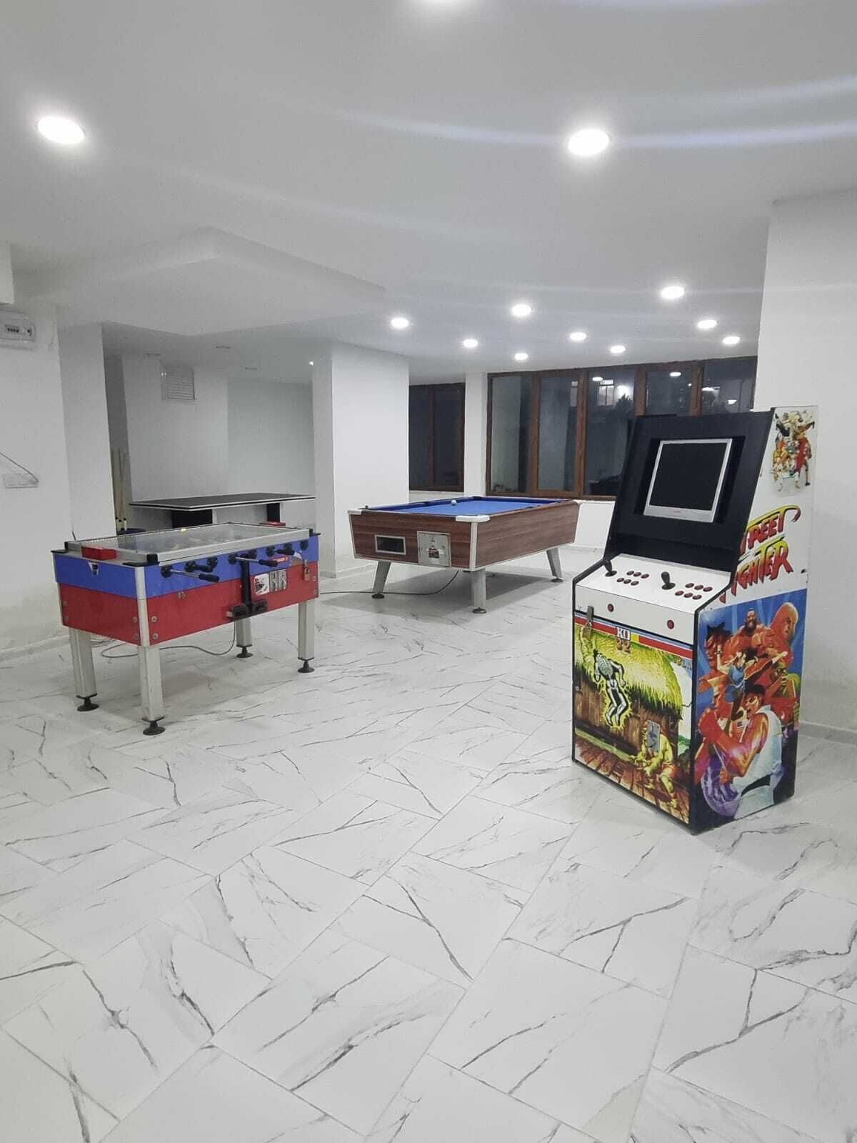 Una habitación con mesa de futbolín, mesa de billar y consola de videojuegos.