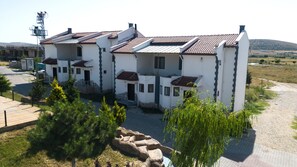 Un immeuble à plusieurs étages, doté d’une façade blanche et d’un toit recouvert de tuiles rouges, et qui présente un escalier en pierre menant à l’entrée.