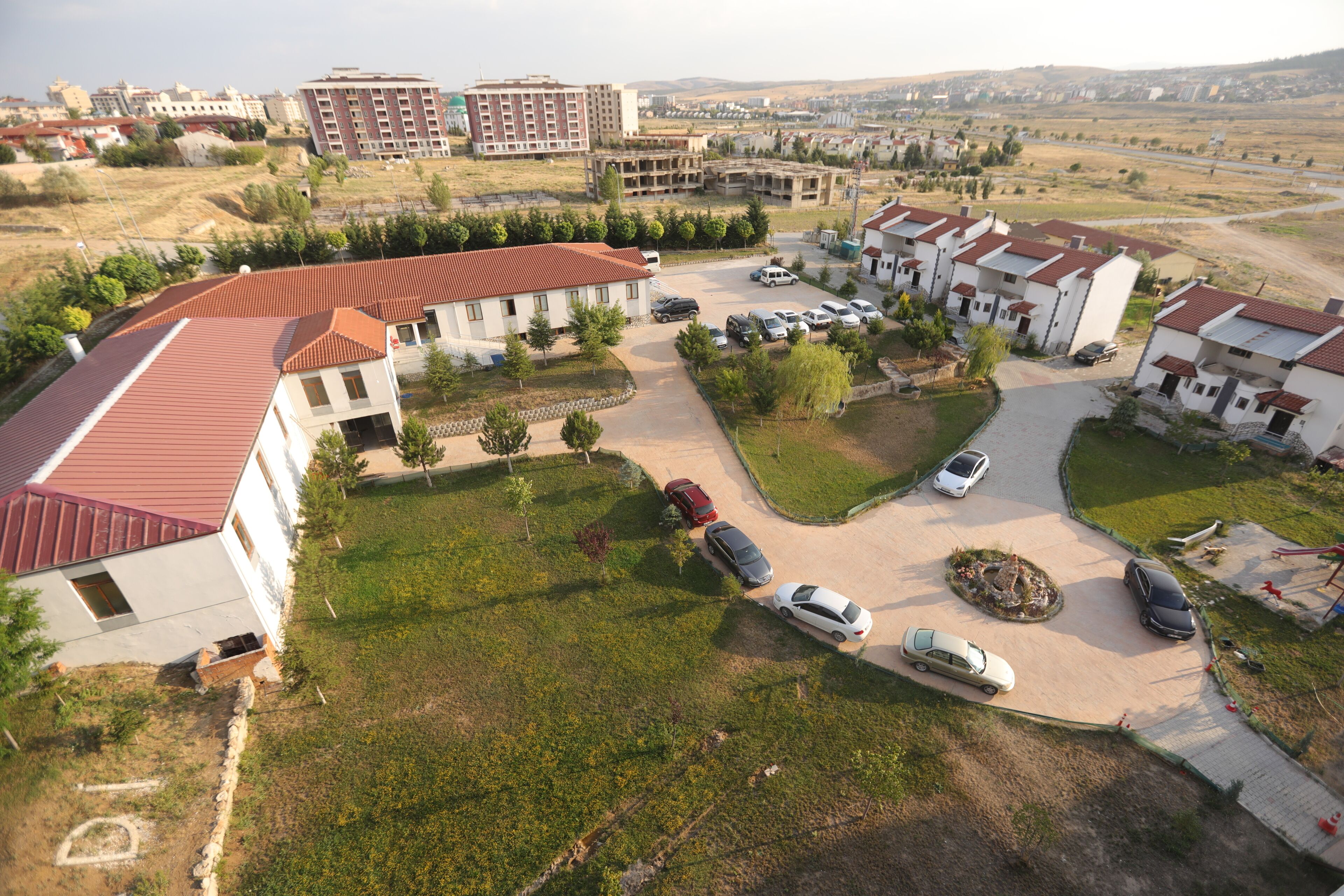Vista aérea de una zona residencial con varios edificios, un estacionamiento y algunos automóviles.