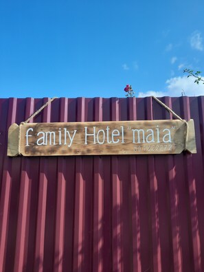 Puinen kyltti, jossa lukee teksti ”Family Hotel Maia” ja on puhelinnumero.