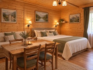 A cozy wooden cabin room with a bed, a sofa, a dining table with chairs, and wall-mounted lamps. - Family hotel Maia (Tsalka)