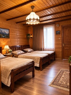 A wooden room with two beds, a chandelier, a painting, and a door. - Family hotel Maia (Tsalka)