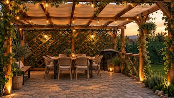 An outdoor patio with a wooden pergola, wicker furniture, and string lights.