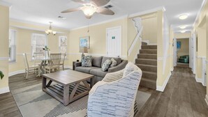 A spacious living room with a ceiling fan, a dining area with a table and chairs, and a staircase leading to another level. - 🌊Private Pool-FREE Beach Service-Near Beach in Windancer--3BR Aloha Cottage🌺 (Miramar Beach)