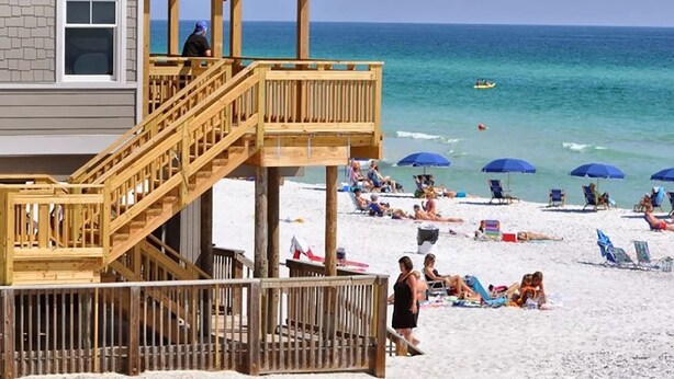 Une maison de plage avec une terrasse en bois et un poste de surveillance pour les sauveteurs.