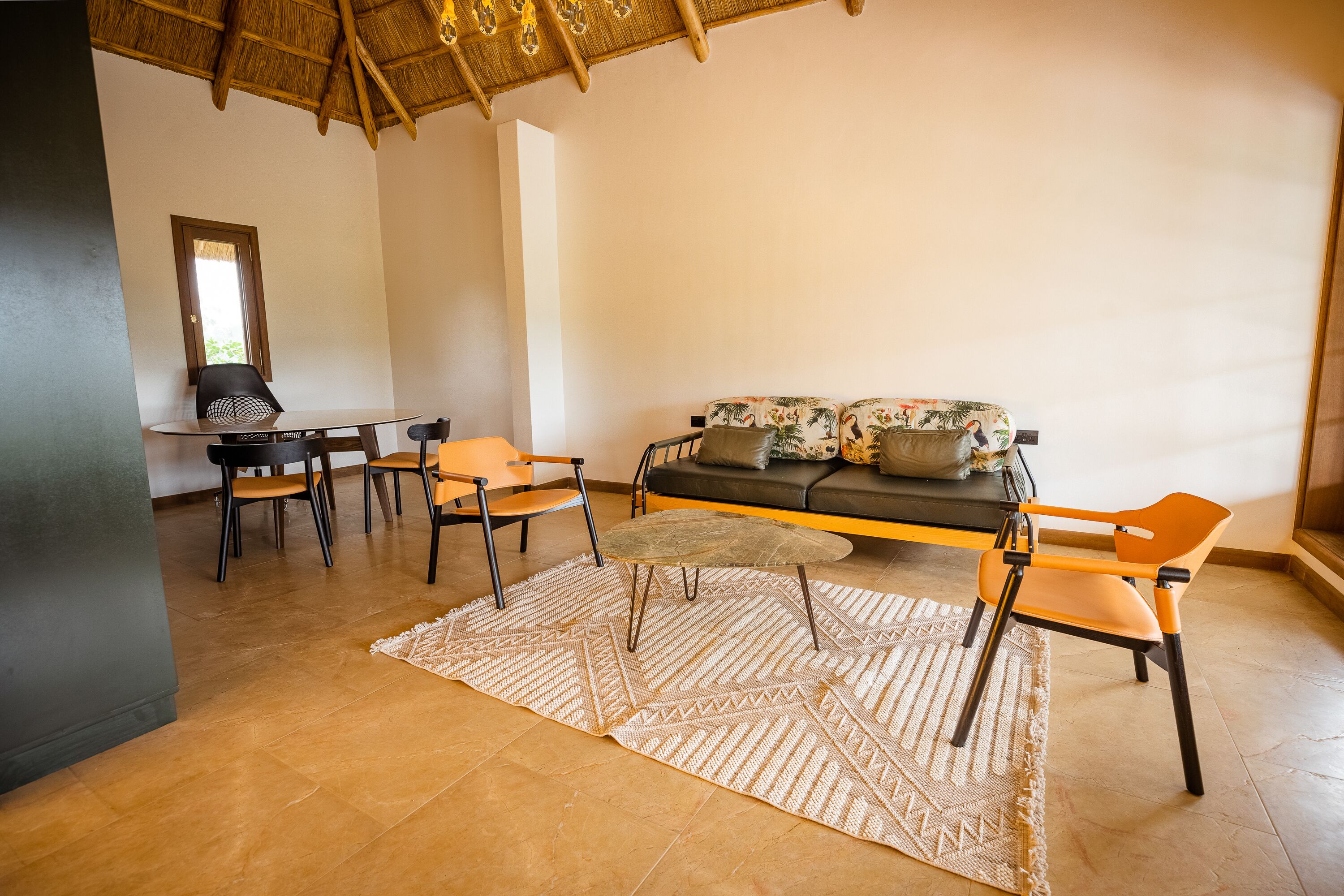 A modern living area with a sofa, chairs, a small table, and a patterned rug.