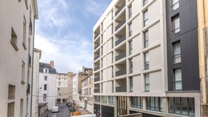 Una calle estrecha con edificios modernos, incluyendo un edificio de varios pisos con balcones y ventanas amplias.
