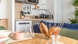 Una mesa de comedor con una cesta de pan, una taza rosa y vasos transparentes.