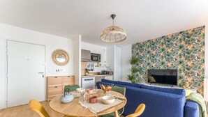Un espacio habitable moderno con comedor, sofá y cocina al fondo.