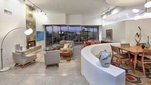 A spacious living area with a fireplace, comfortable seating, and a large window offering a view of the outdoors.