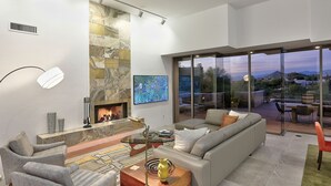 A modern living room with a fireplace, comfortable seating, and a glass door leading to an outdoor patio.